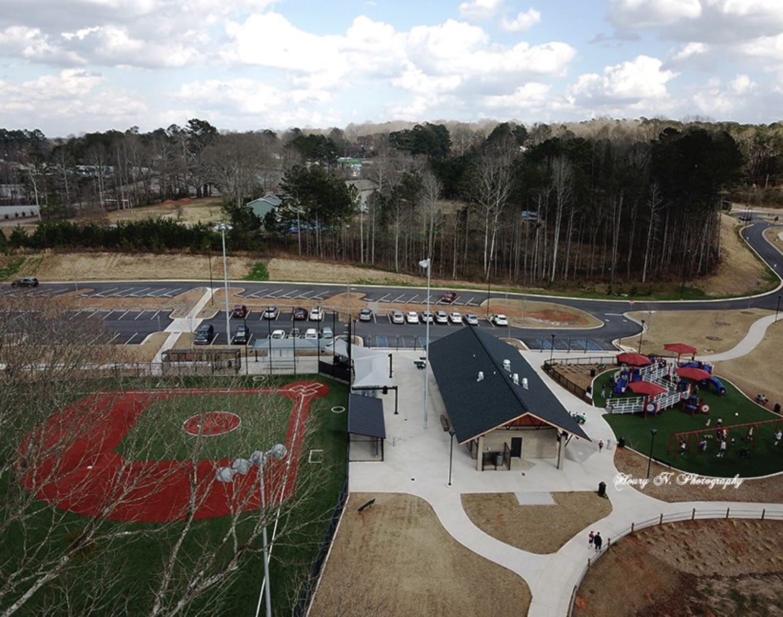 Aerial view of a community park featuring a baseball field, playground, and pavilion.