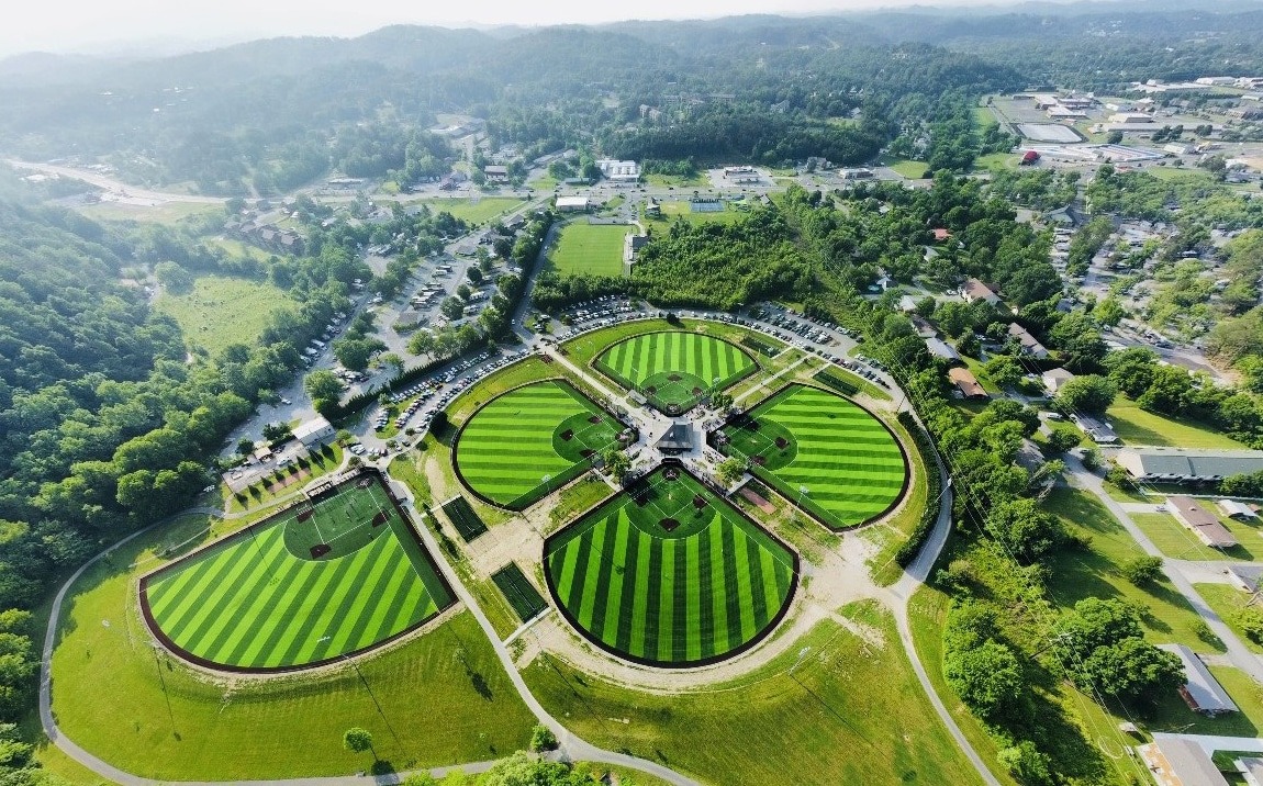 Aerial view of a sports complex with multiple baseball fields surrounded by greenery.