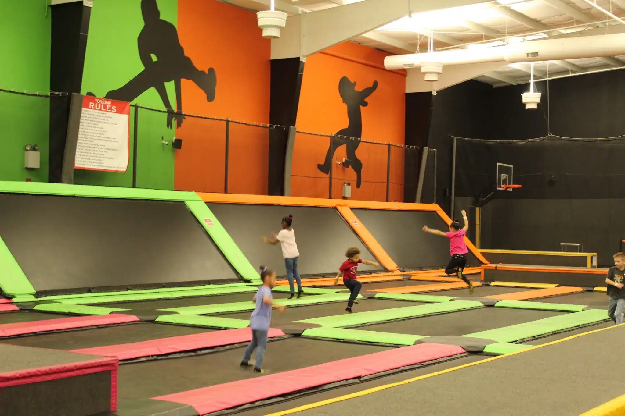 Children jumping on interconnected trampolines at an indoor trampoline park.