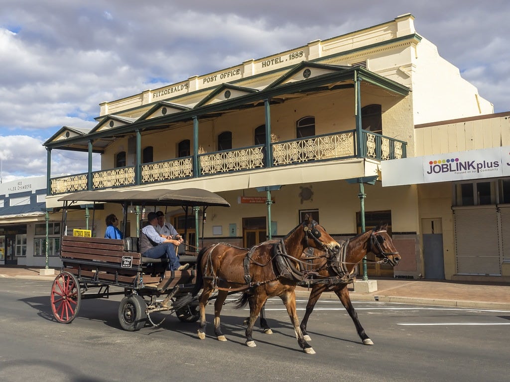 Horse-drawn carriage passing by a historic 1888 hotel in a small town.