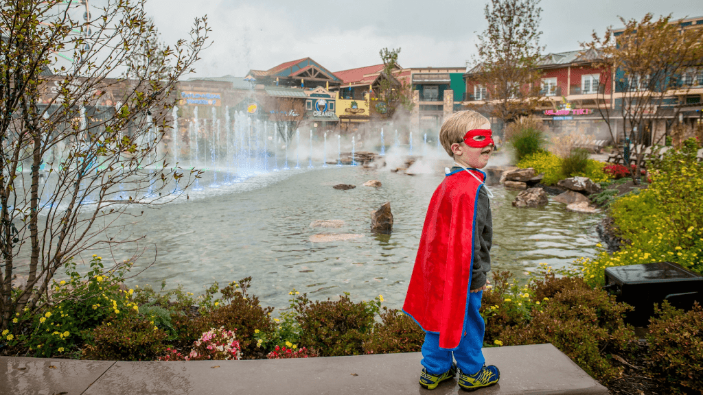 Boy in red superhero cape and mask watching dancing fountains during Halloween at the Island Pigeon Forge.